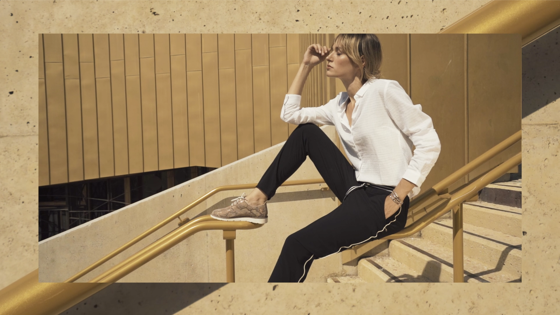 Femme décontractée qui pose dans des escaliers assise sur une rambarde